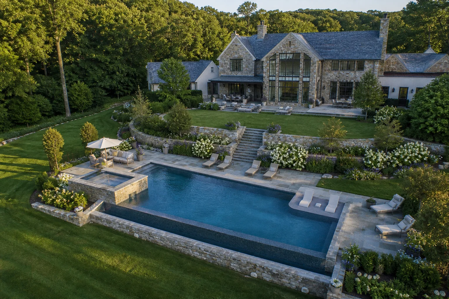 Finished aerial view of a luxury gunite pool, spa, stone terrace, and estate landscaping
